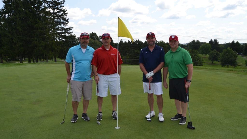 Four men posing for picture on golf course