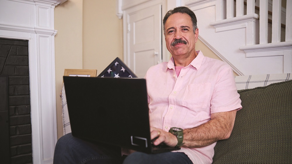 A person sits on their couch as they use their laptop.