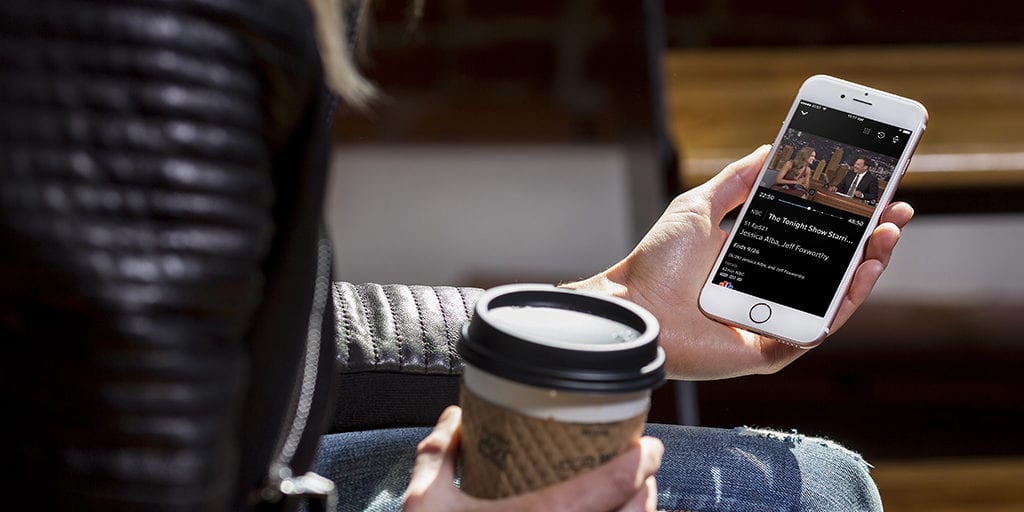 college student looking at movie on her smartphone while holding a cup of coffee