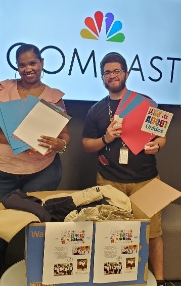 two employees holding donated uniforms