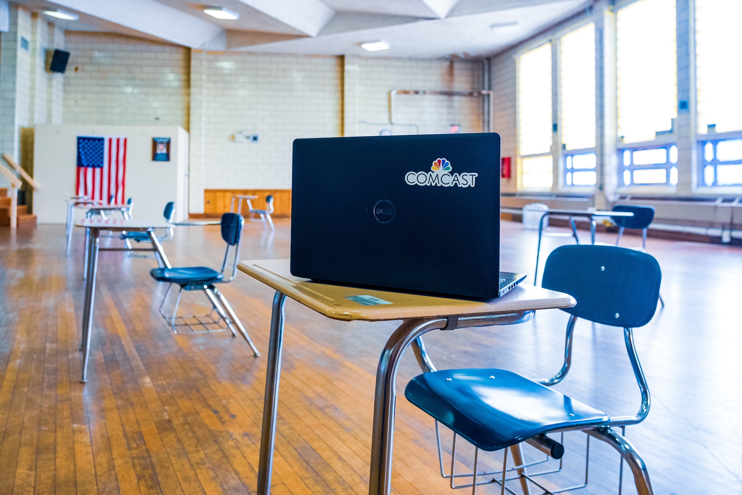 laptop with Comcast logo sitting on student desk in classroom