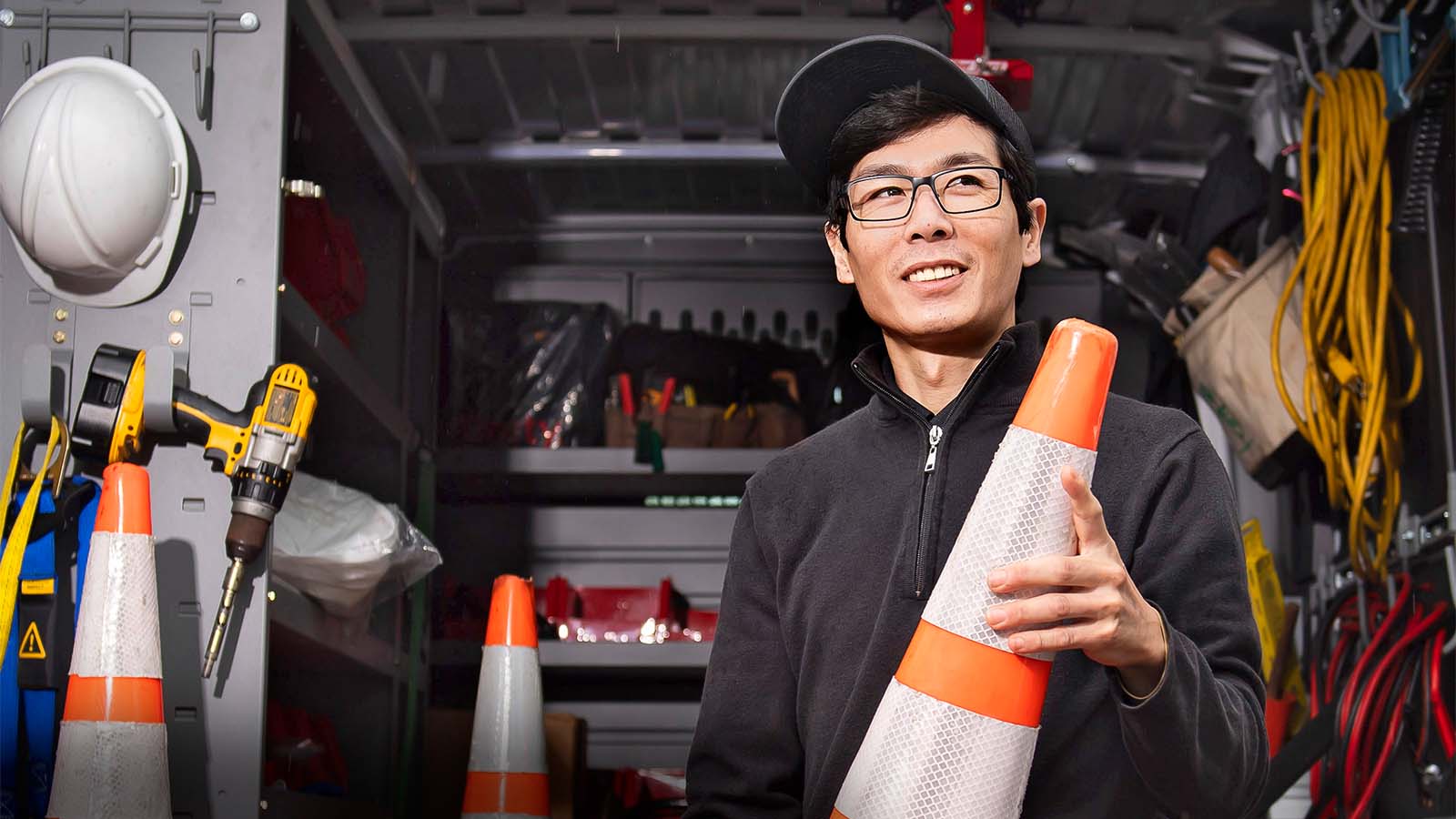 Technician holding orange cone outside his truck