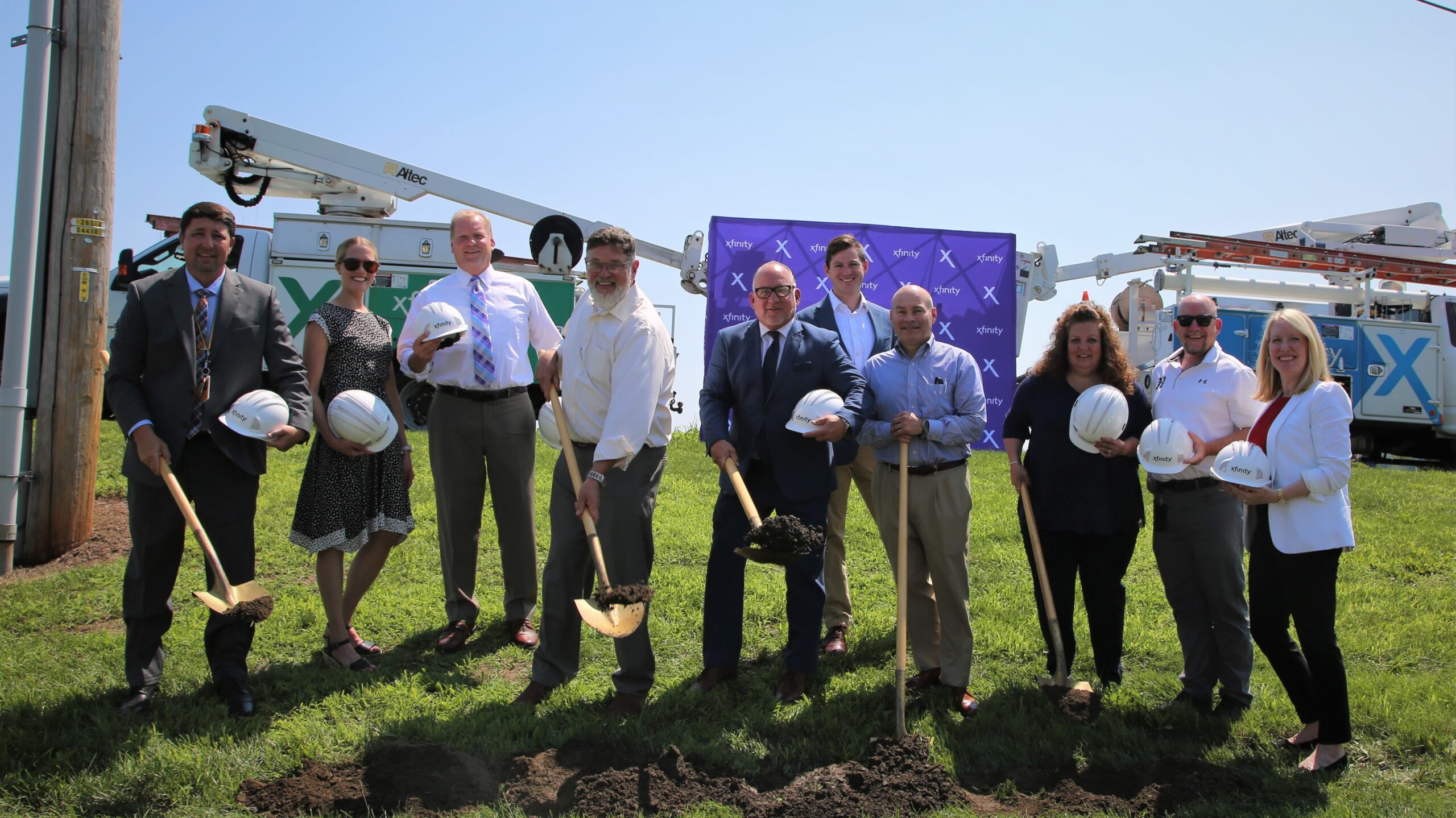 Group holding hardhats and digging dirt with shovels